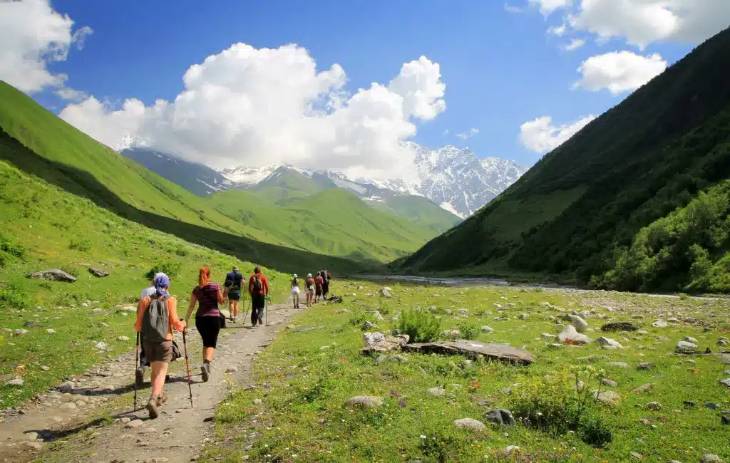 Wanderer in Berglandschaft mit Wiese und Wolken