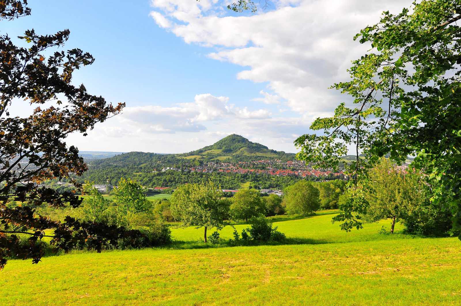 Grüne Landschaft mit Hügeln und blauem Himmel.