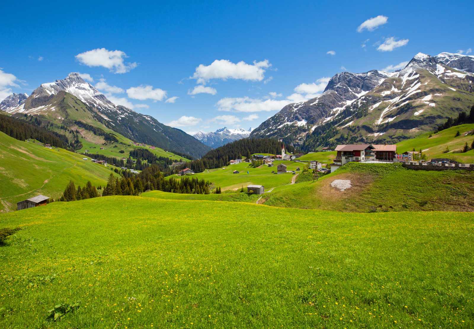 Berglandschaft mit grünen Wiesen und Dorf im Tal.