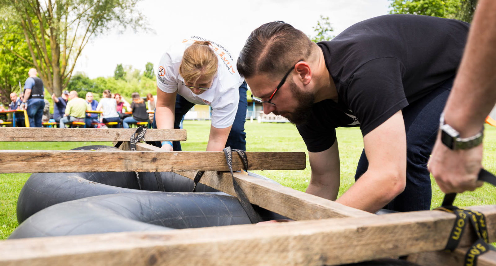 Menschen bauen ein Floß auf einer Wiese.