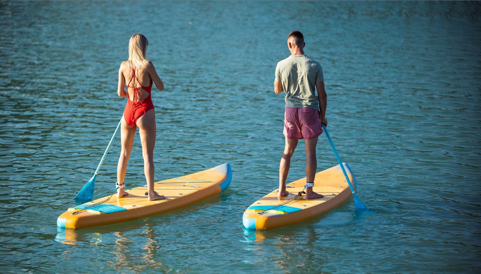 Zwei Personen paddeln auf Stand-Up-Paddleboards.